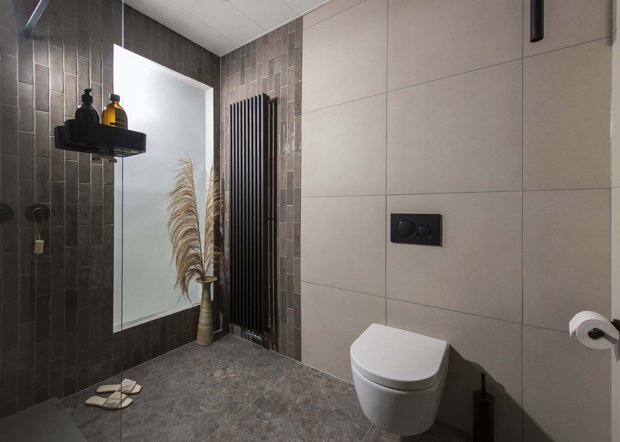 Wit hangtoilet naast een zwarte designradiator